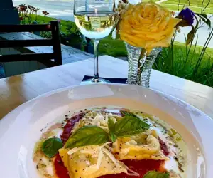 Ravioli dish and a glass of wine. 